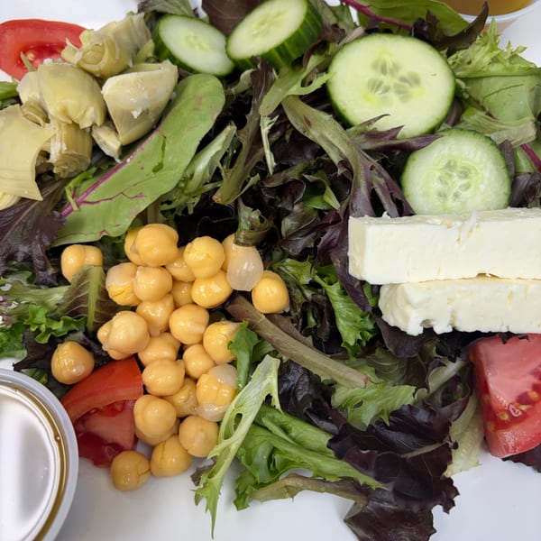Close-up of a fresh garden salad with chickpeas, artichoke hearts, cucumbers, tomatoes, and feta cheese.
