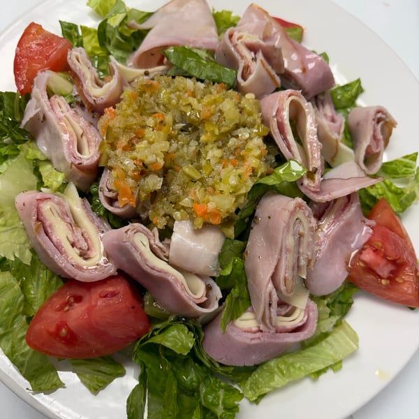 Ham and cheese roll-ups with relish and tomato wedges on a bed of lettuce.