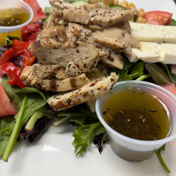 Grilled chicken salad with feta, chickpeas, tomatoes, peppers, and two cups of dressing.