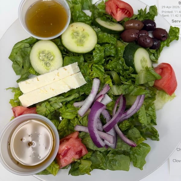 A fresh Greek salad with lettuce, cucumbers, tomatoes, olives, feta cheese, and red onions.