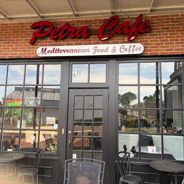 Exterior of Petra Cafe, a Mediterranean restaurant, with outdoor seating and an "Open" sign.